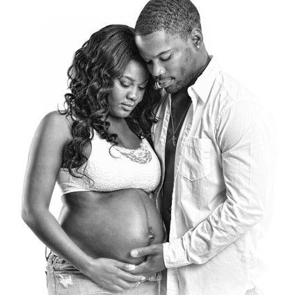 A man and a pregnant woman are hugging each other in a black and white photo.
