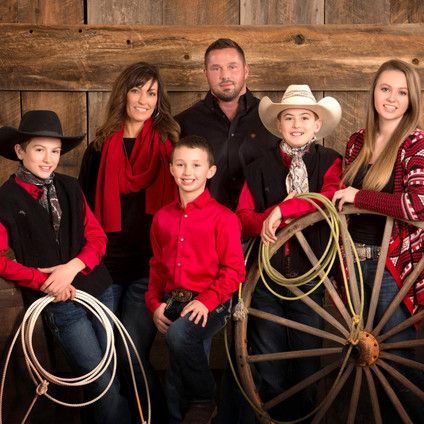A family posing for a picture with a wagon wheel and ropes.