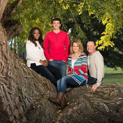 A family is posing for a picture while sitting on a tree branch.