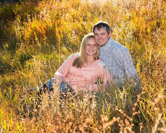 A man and a woman are sitting in a field of tall grass.