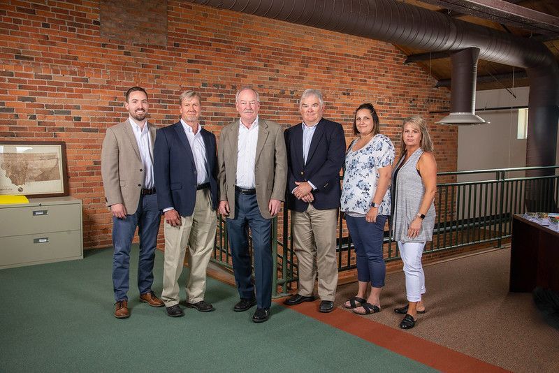 A group of people standing next to each other in front of a brick wall.