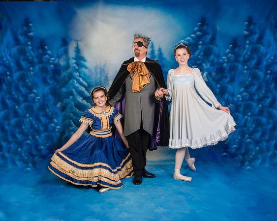 A man and two girls are posing for a picture in front of a blue background.