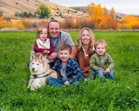 A family is sitting in the grass with a dog.
