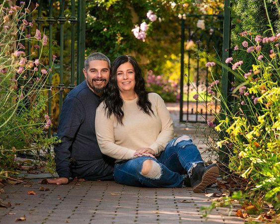 A man and a woman are sitting next to each other on a sidewalk.