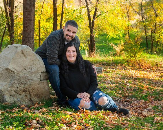 A man and a woman are sitting on a rock in the woods.