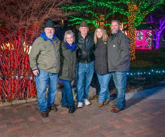 A group of people are posing for a picture in front of christmas lights.