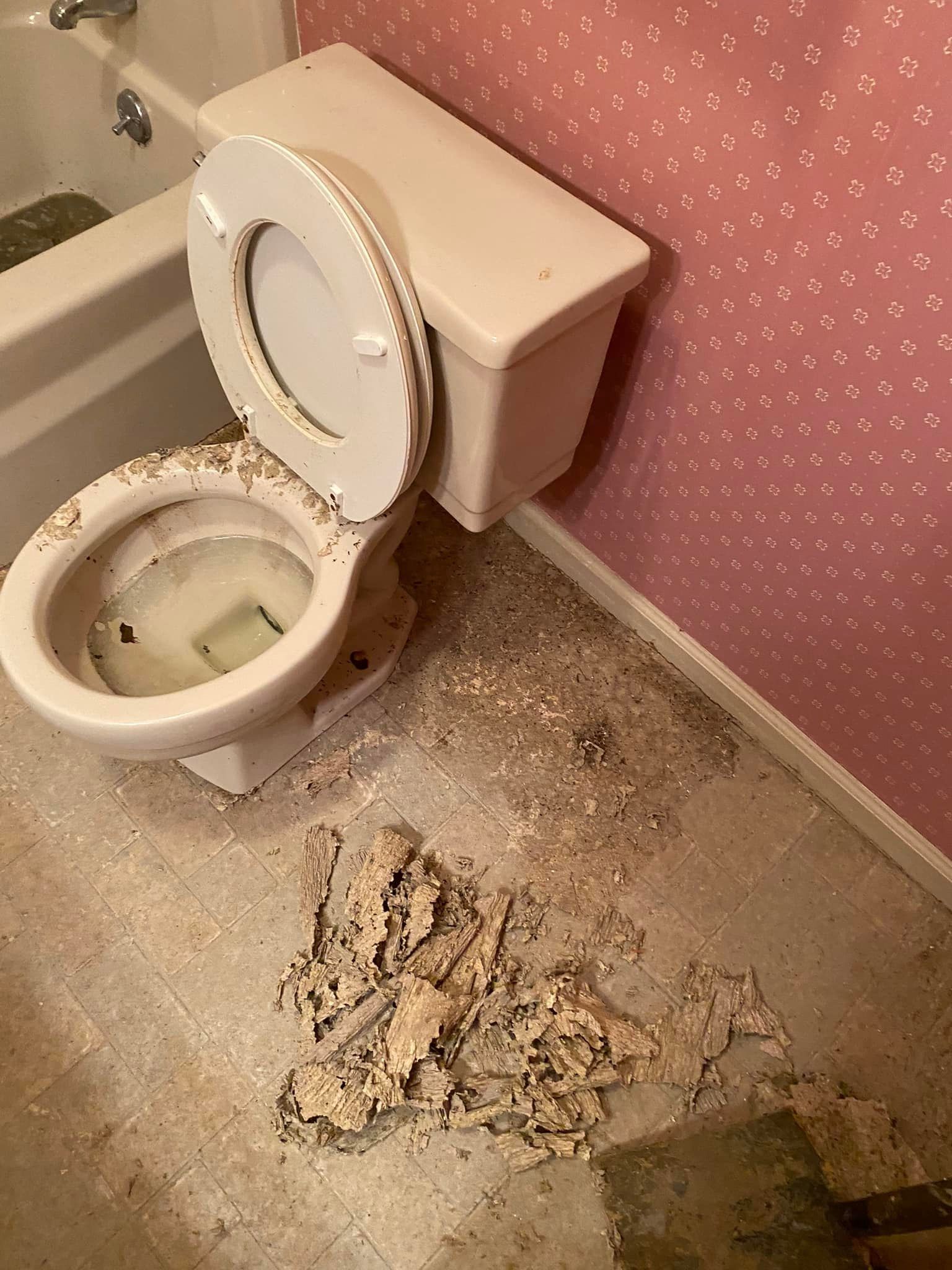 A toilet is sitting on the floor in a bathroom next to a bathtub.
