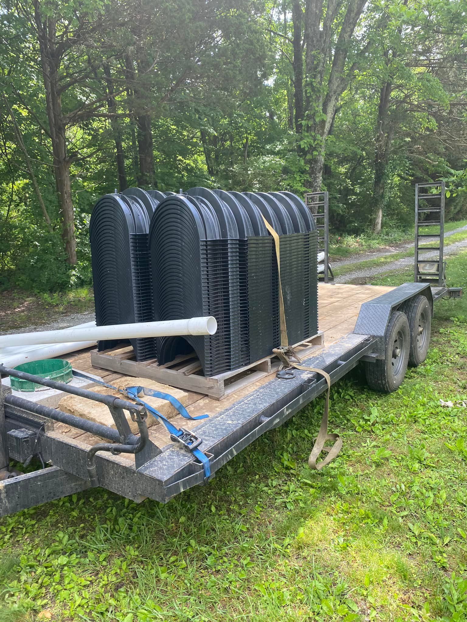 A trailer filled with a bunch of plastic containers and pipes.