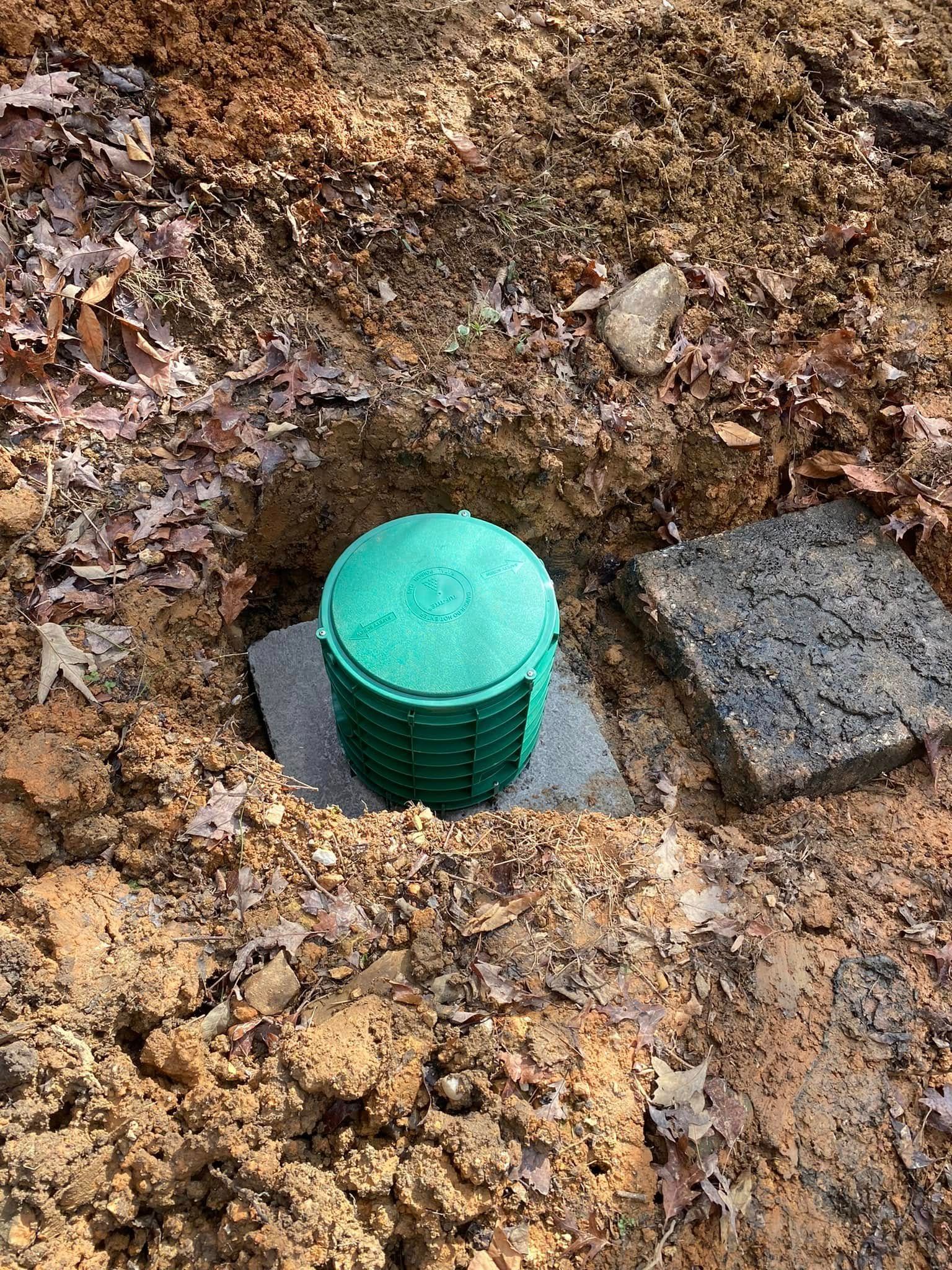 A green container is sitting in the middle of a pile of dirt.