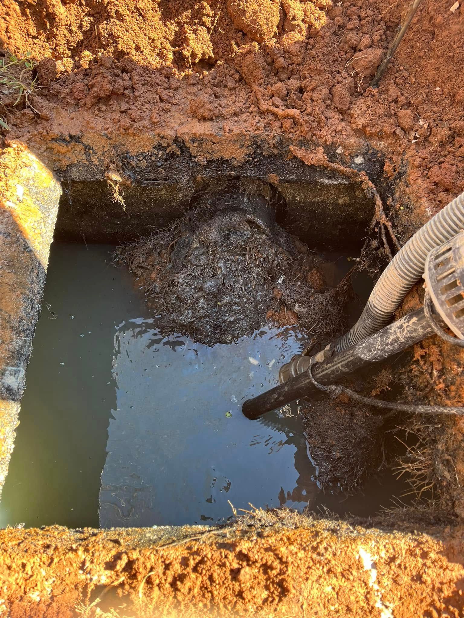A hose is being used to pump water out of a hole in the ground.