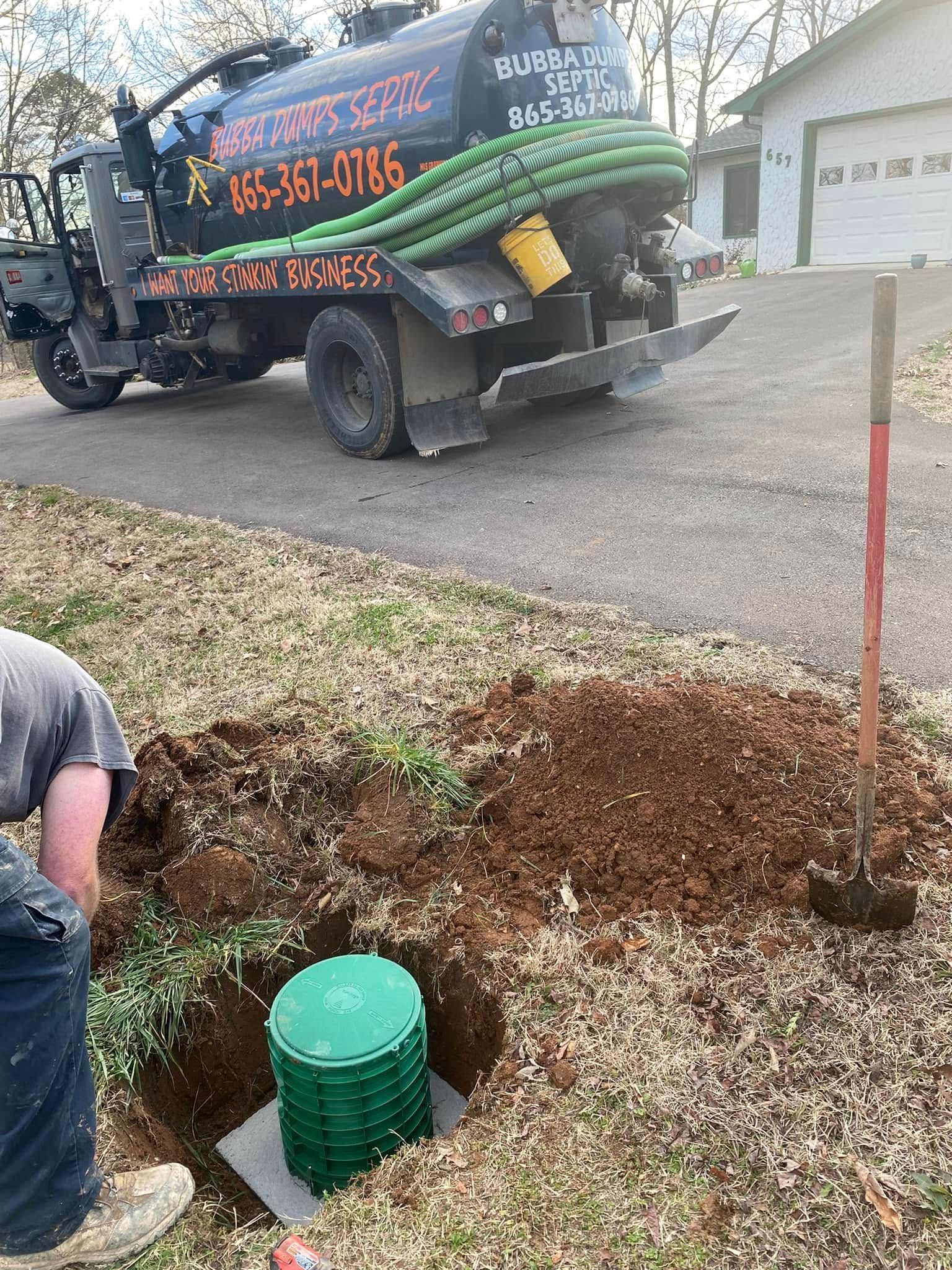 A man is digging a hole in the ground next to a vacuum truck.