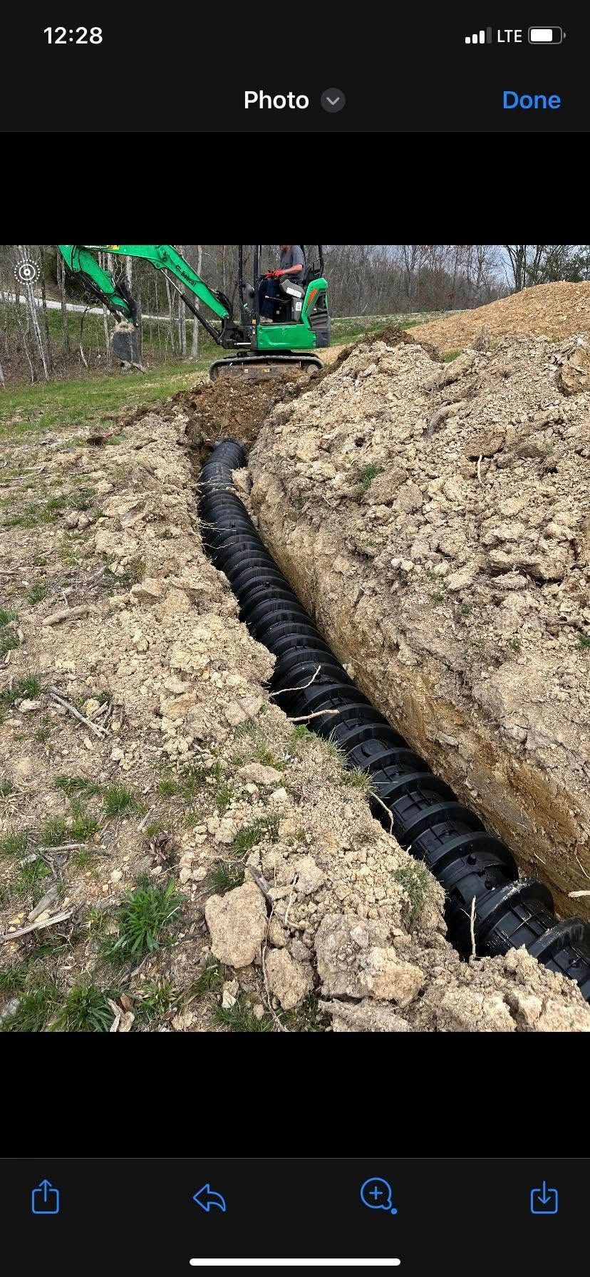 A man is digging a hole in the ground with a green excavator.