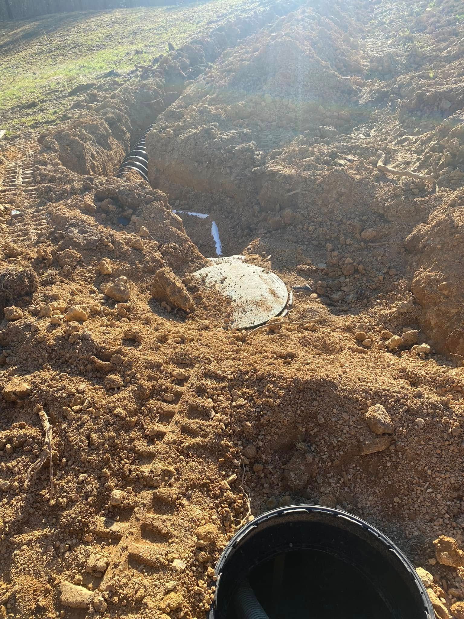 A black bucket is sitting in the dirt next to a hole in the ground.