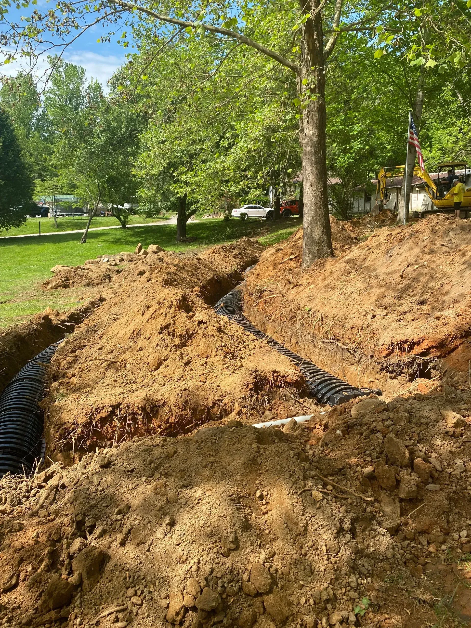 A large pile of dirt is sitting in the middle of a park next to a tree.