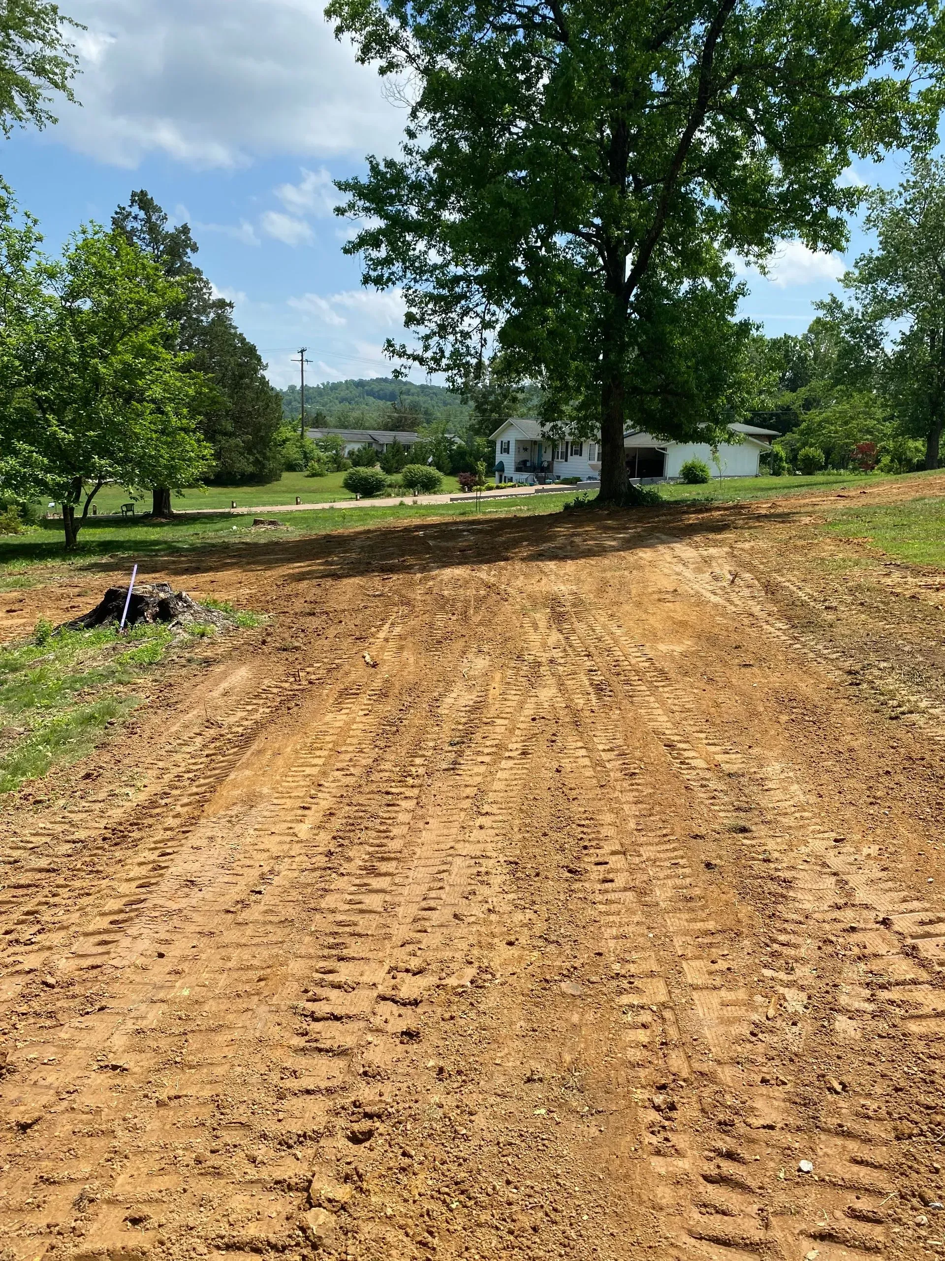 A dirt road leading to a house with trees in the background.