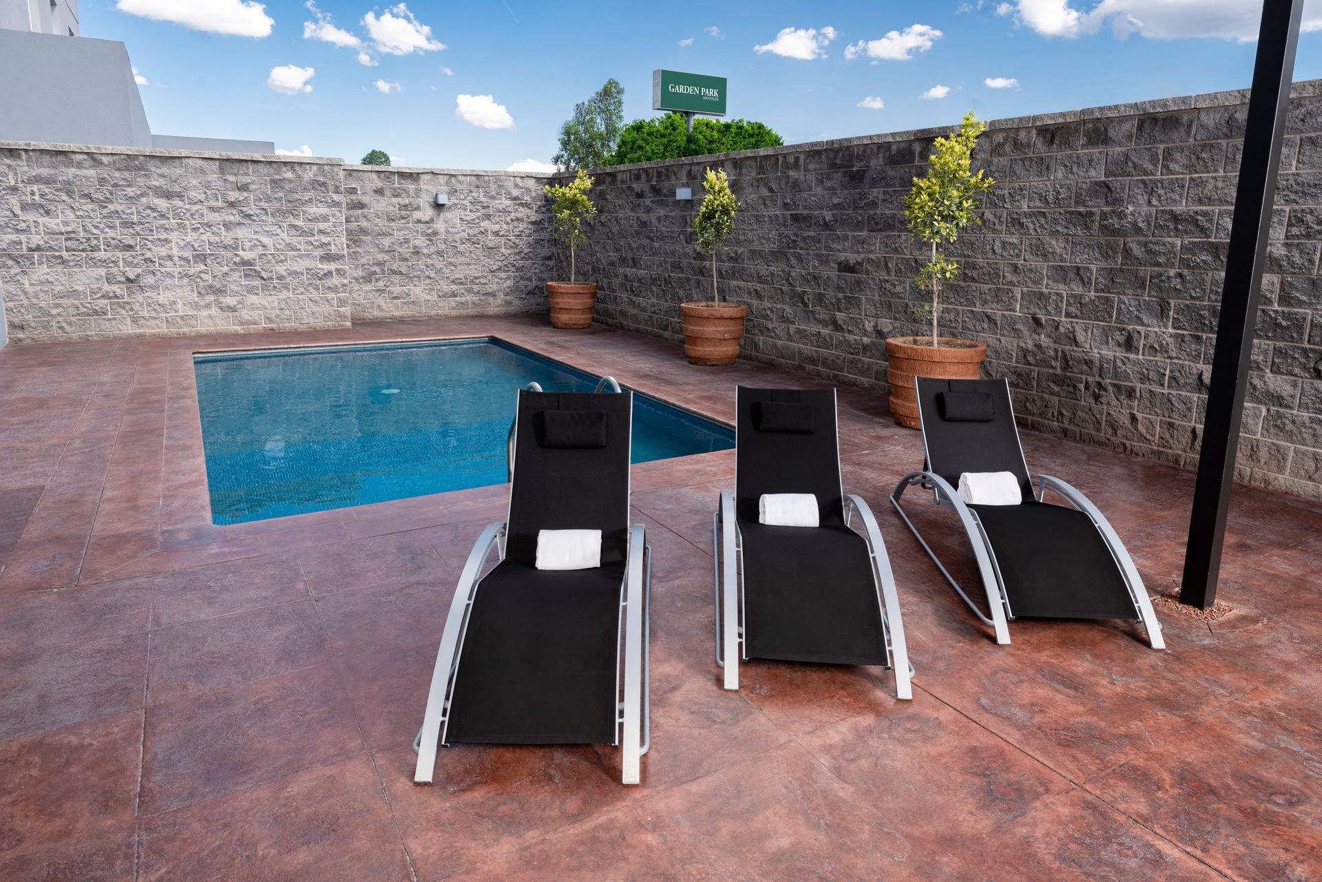 Tres sillones negros frente a una piscina