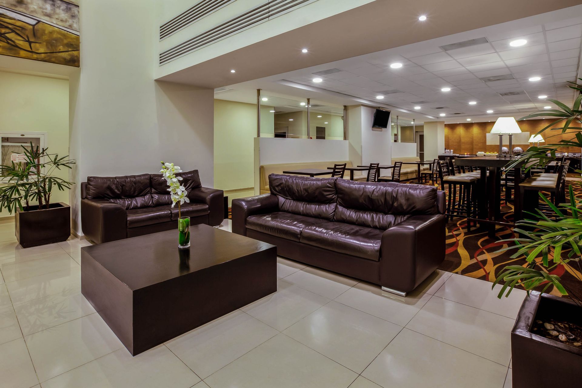 There are two couches and a coffee table in the lobby of a hotel.