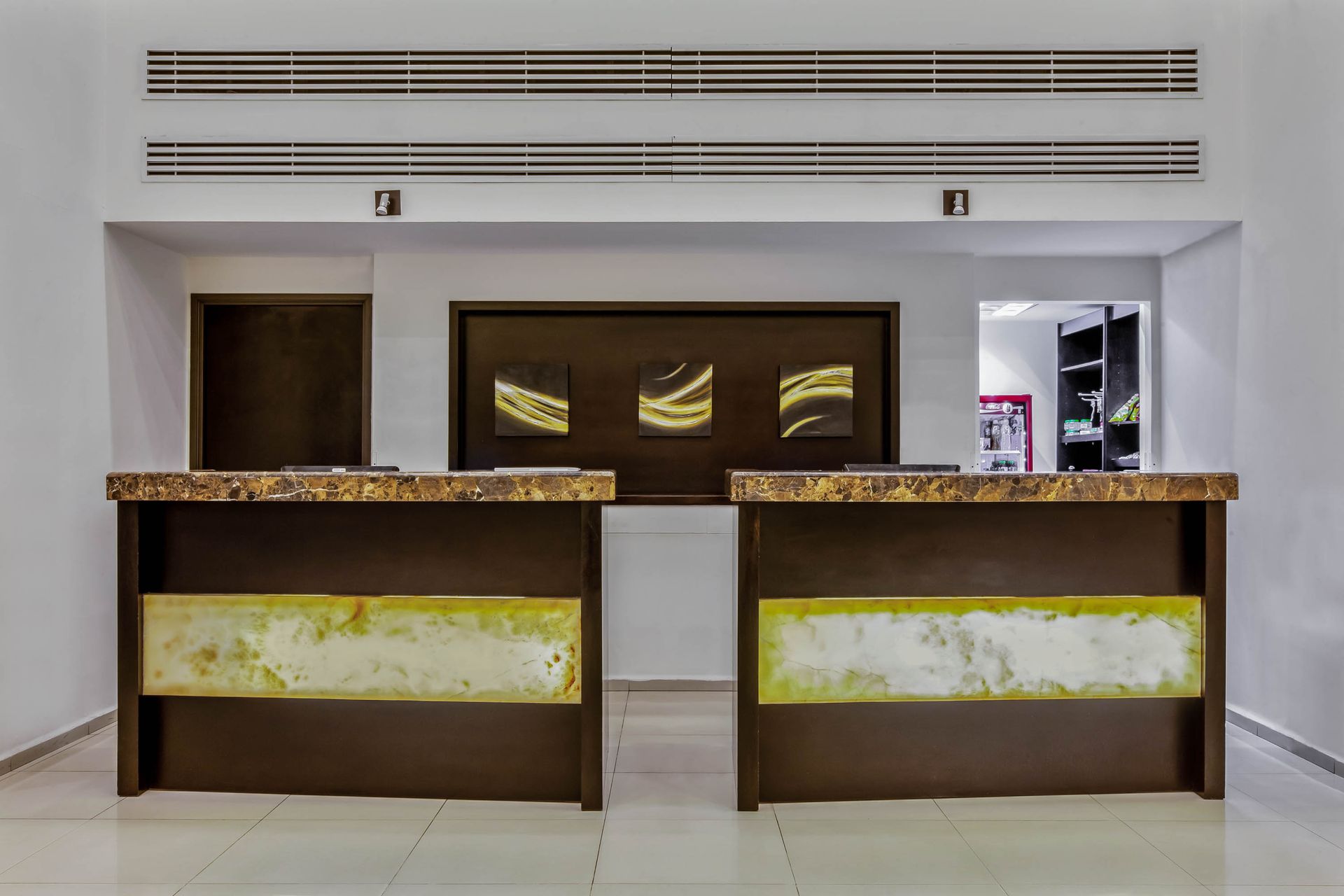 A hotel lobby with two reception desks and a ceiling fan.