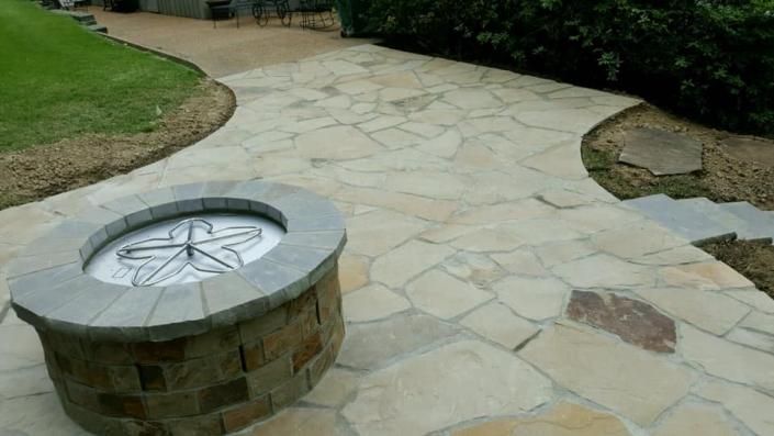 Stone patio with a circular bench surrounding a decorative compass-like metal inset.