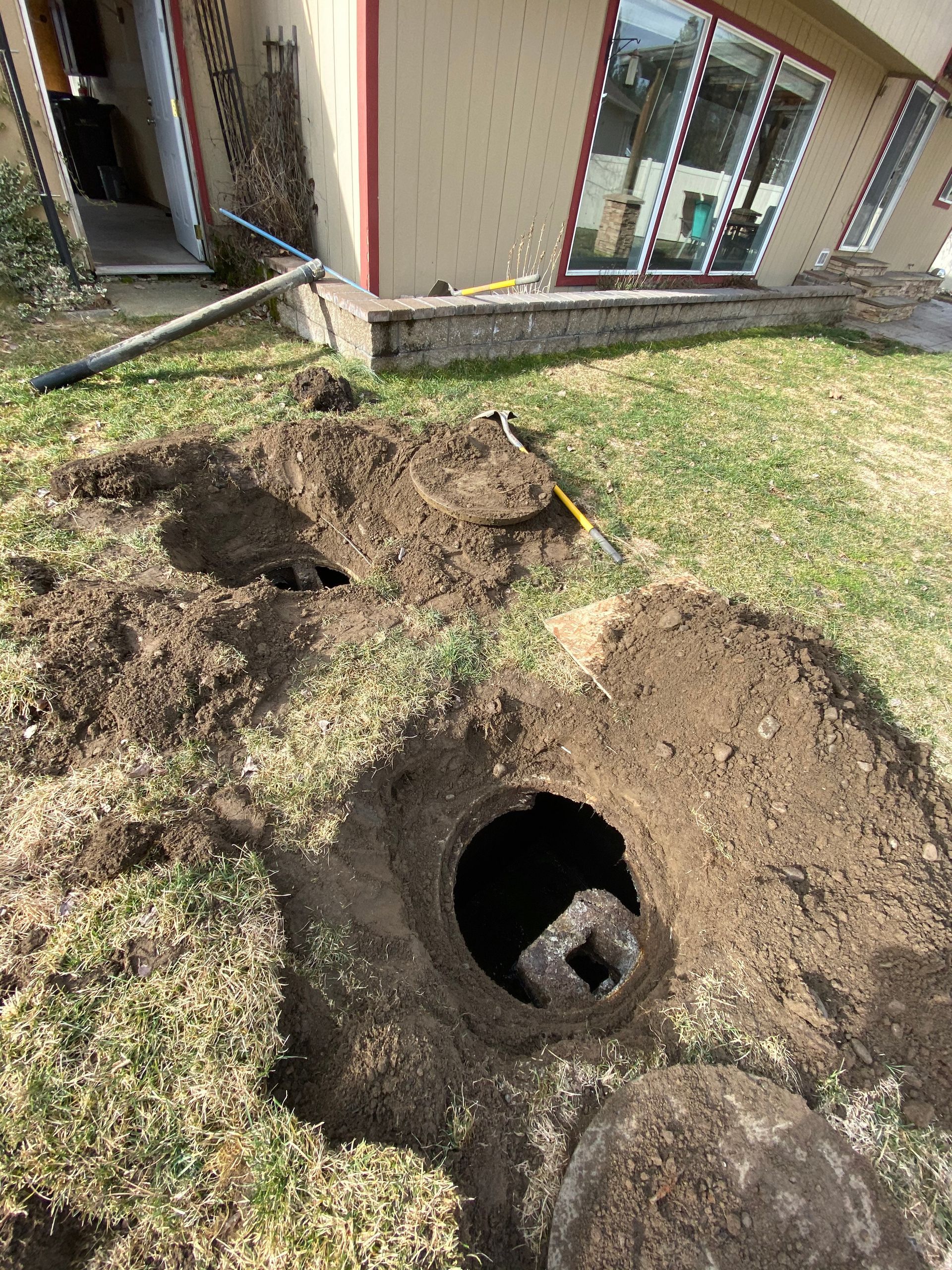 A man is pumping water into a manhole cover with a hose.