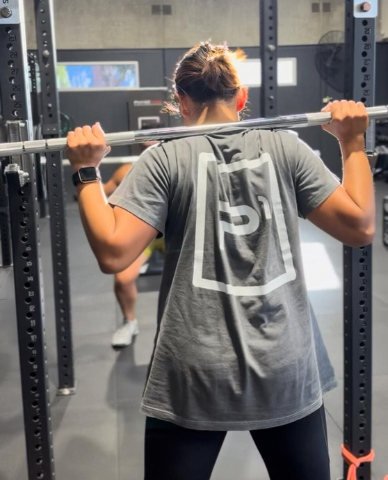 Man watches woman lifting weight in a gym setting.