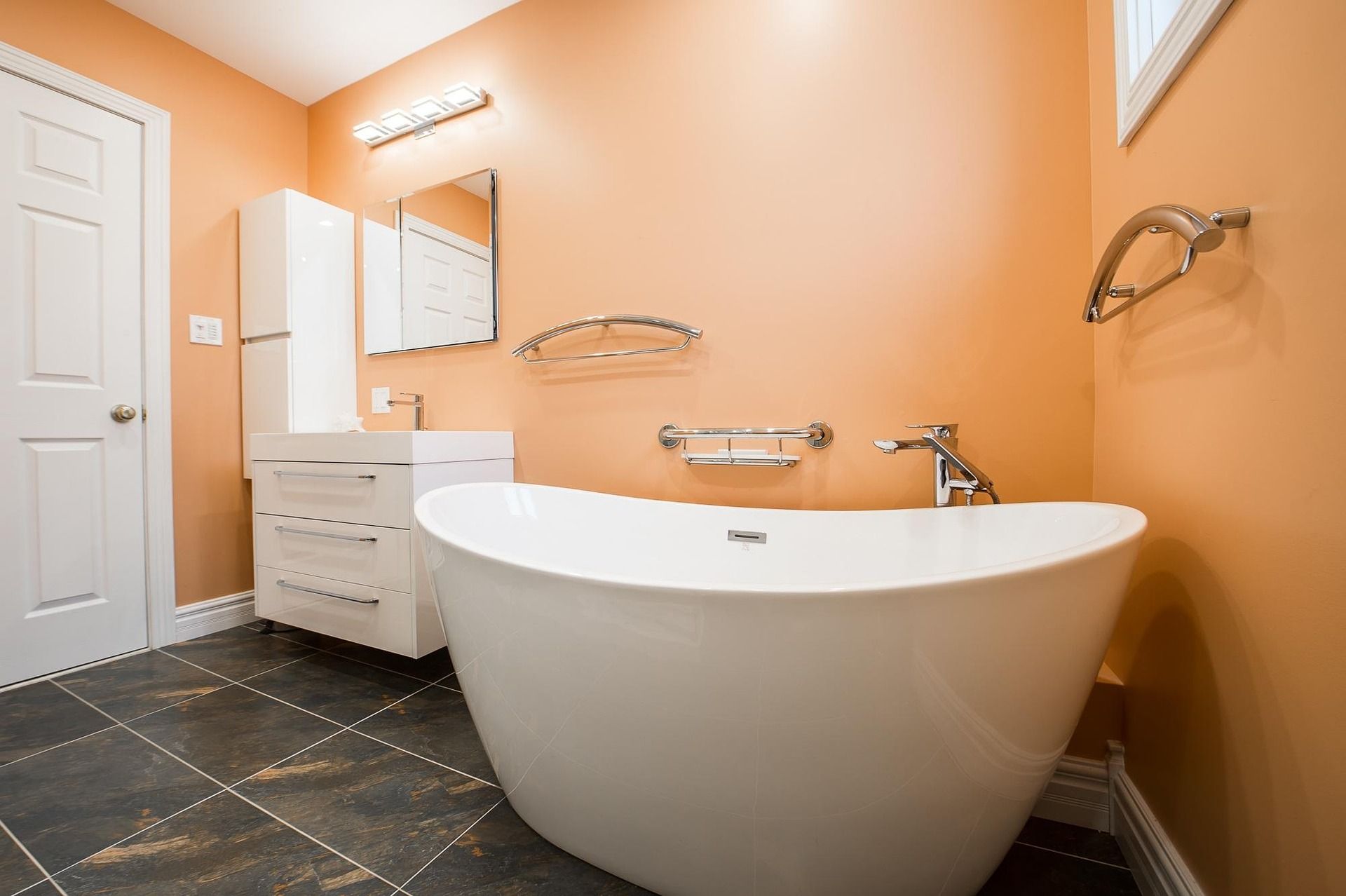 orange bathroom with tub, sink, and a door