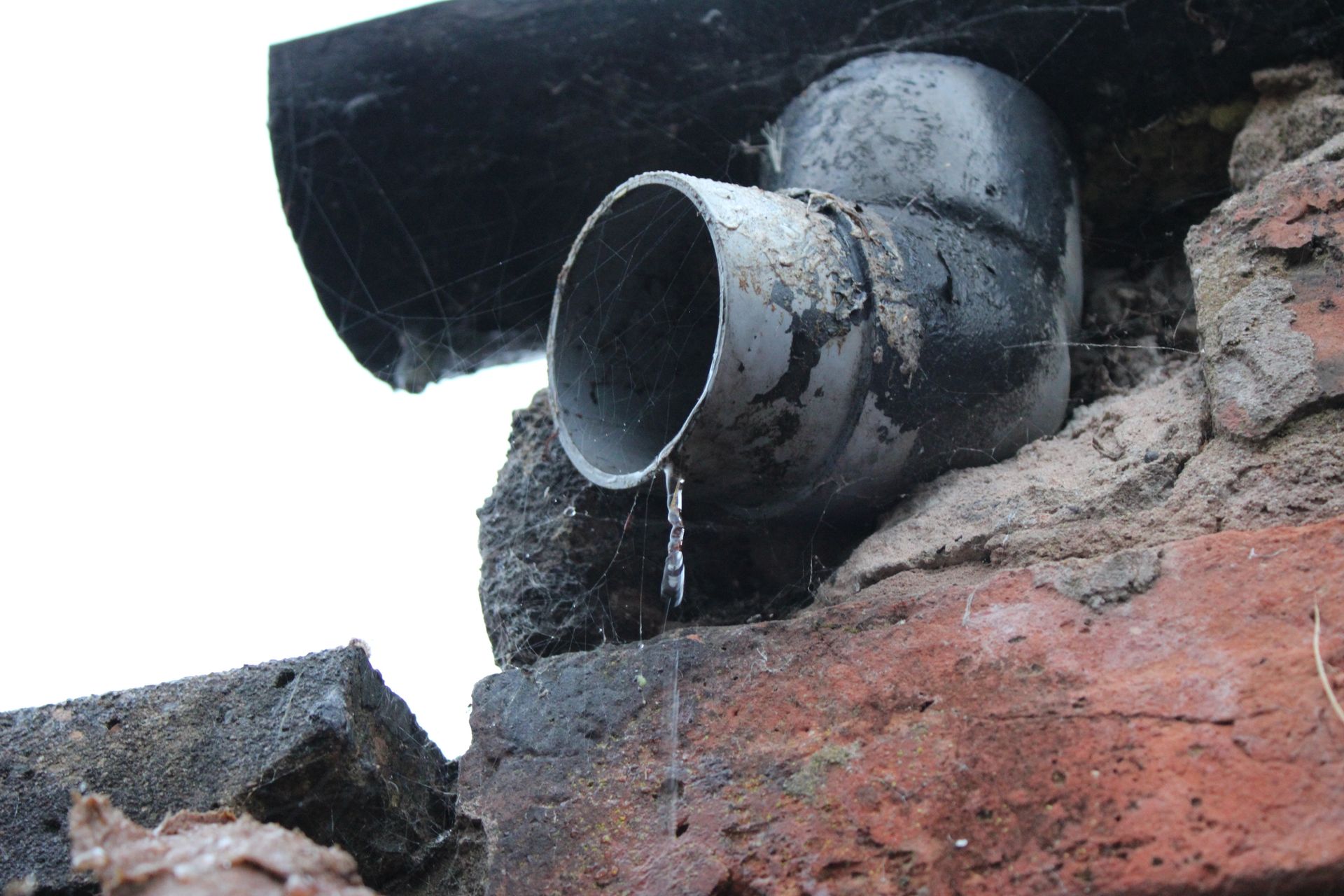 A drainpipe is sitting on top of a brick wall – Seguin, TX – 5J Plumbing