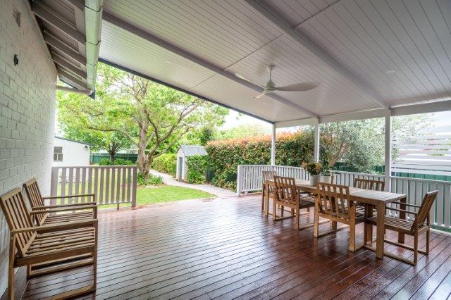 A porch with a table and chairs and a ceiling fan
