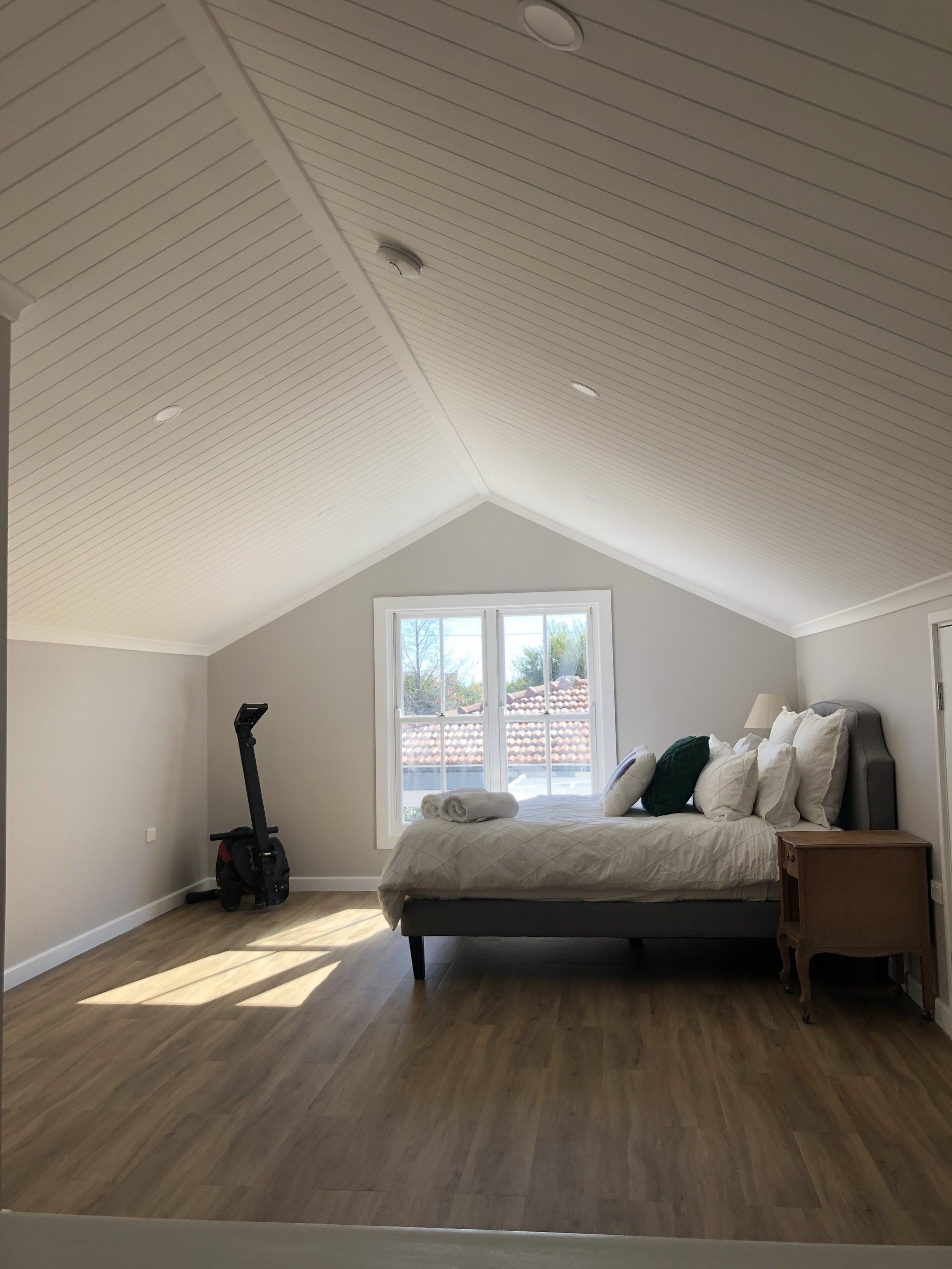 A bedroom with a vaulted ceiling and a large bed.