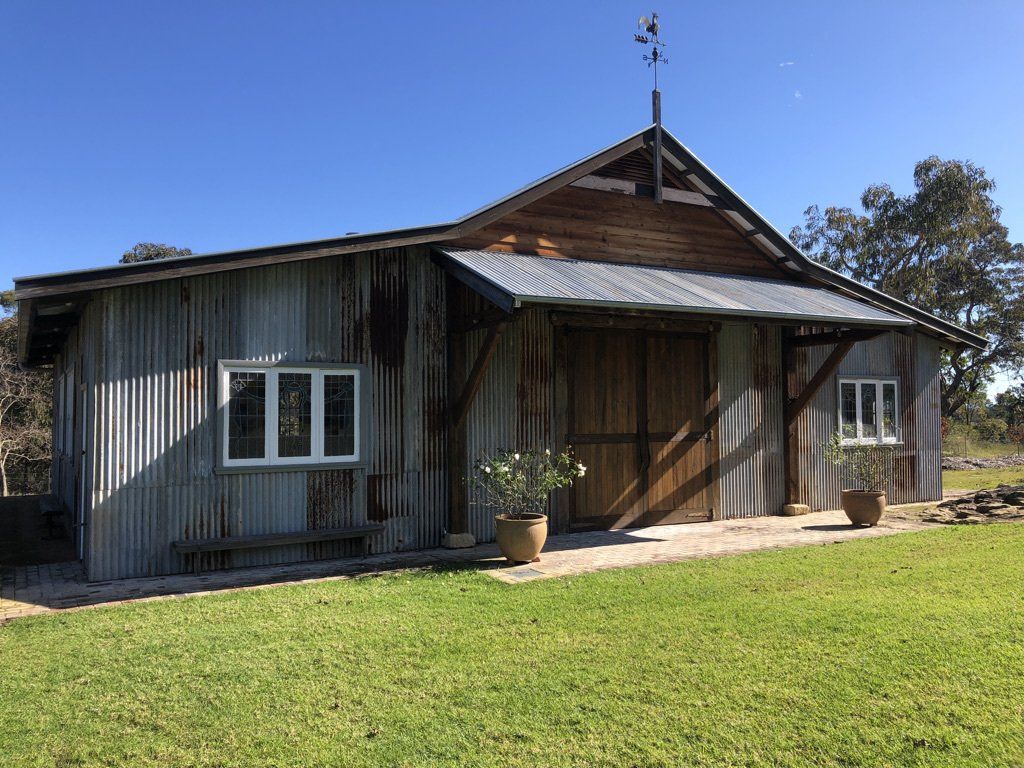 A small house with a tin roof is sitting in the middle of a grassy field.