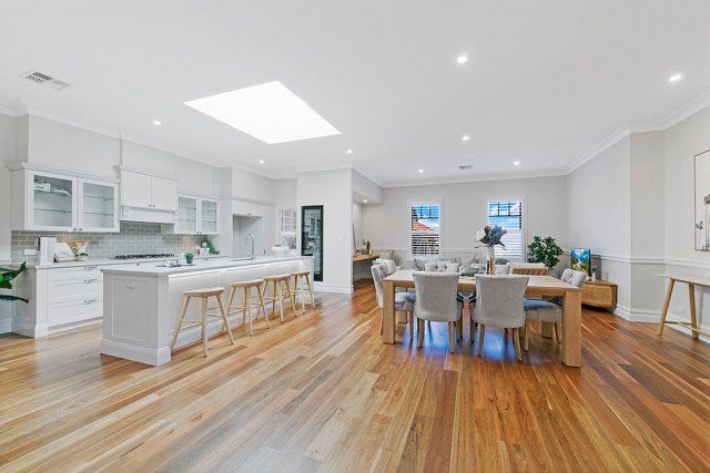 A kitchen and dining room in a house with hardwood floors and white cabinets.