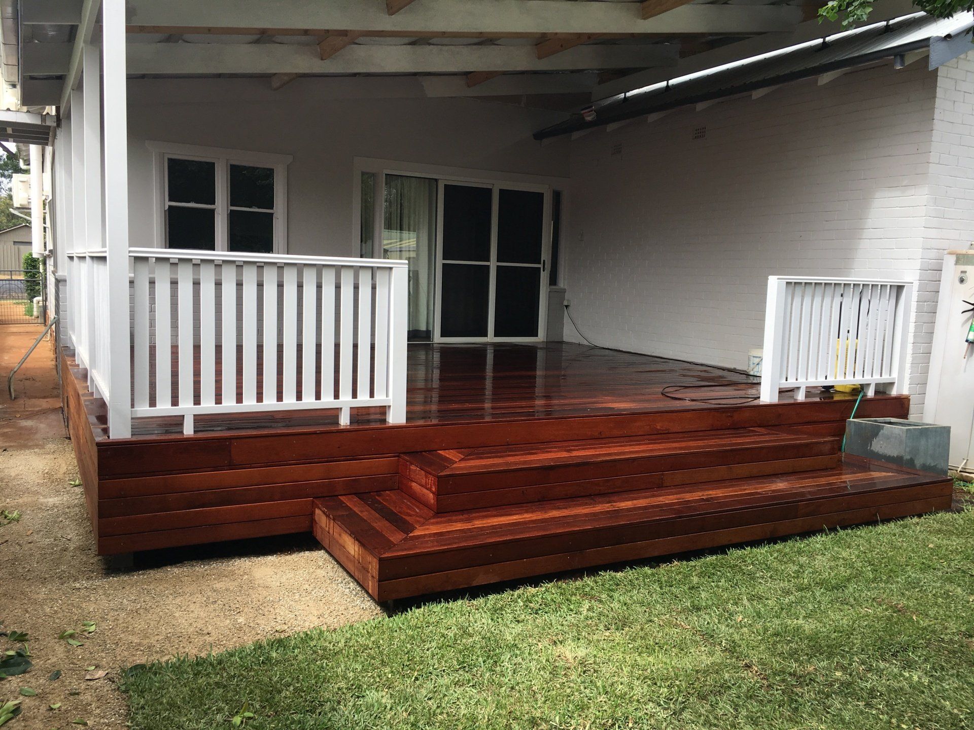 A wooden deck with stairs is in front of a white house.