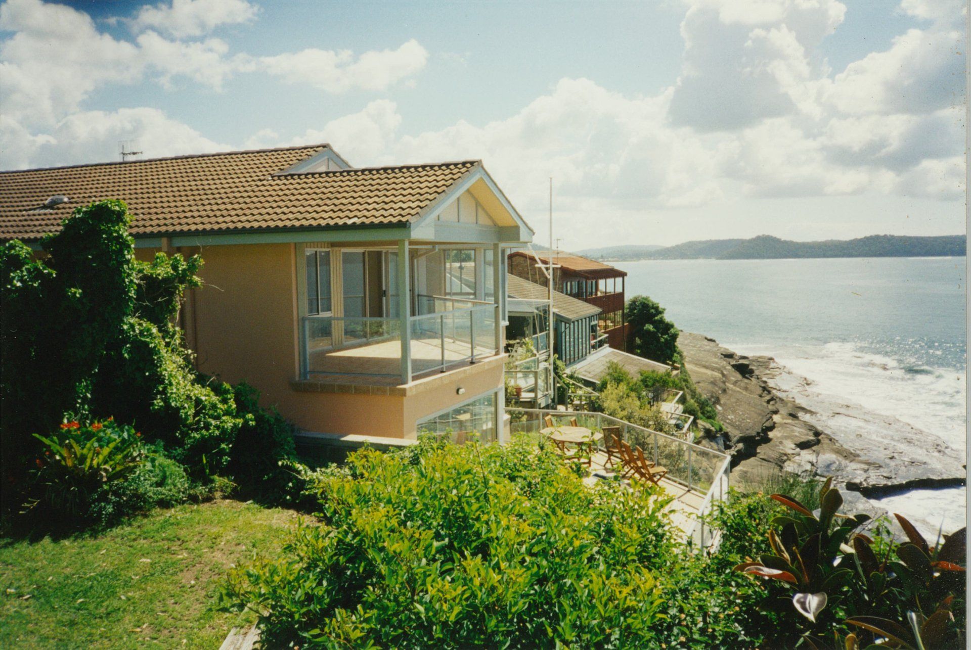 A house sits on a cliff overlooking the ocean