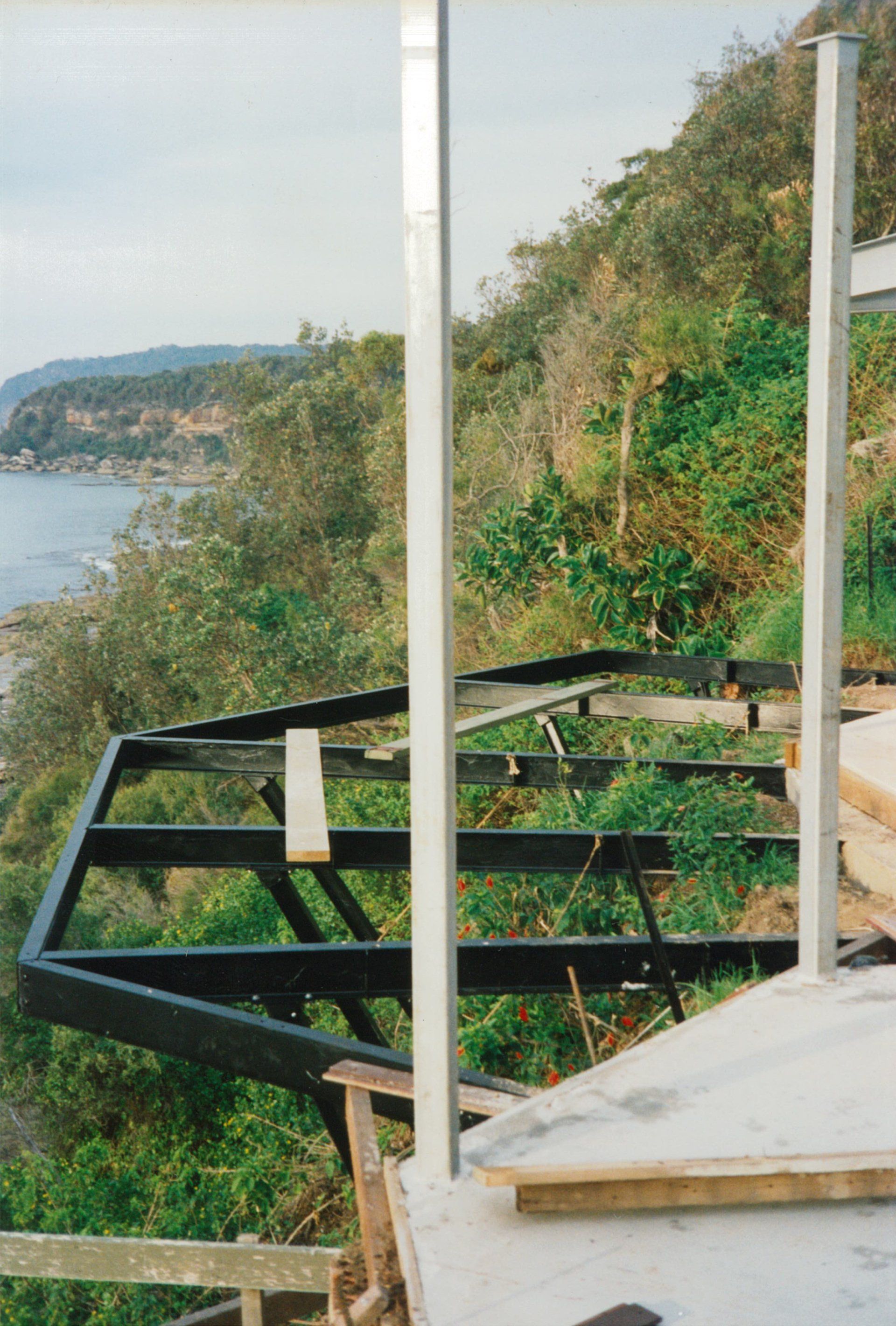A metal structure is being built on a hill overlooking the ocean