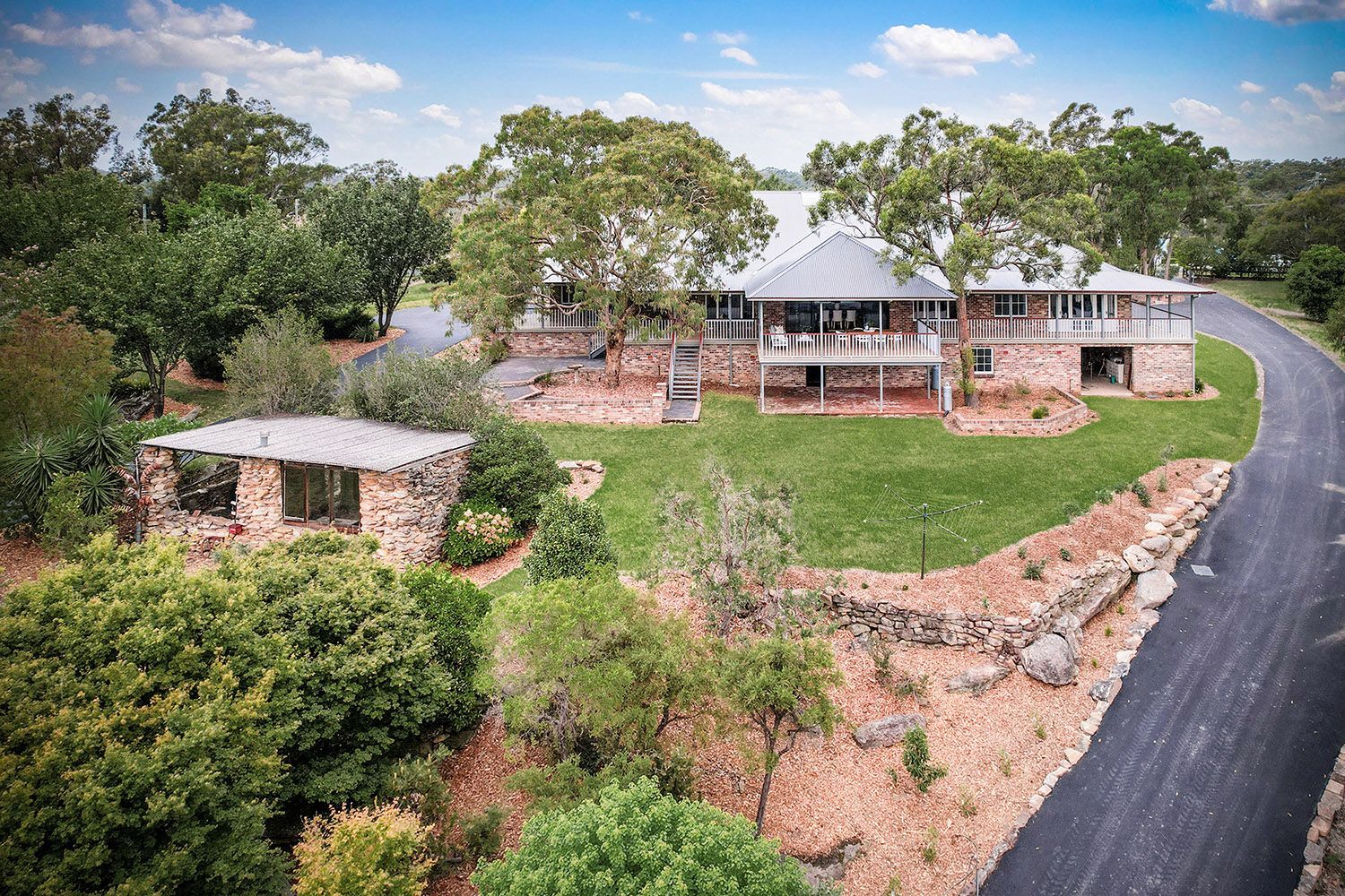 An aerial view of a large house surrounded by trees and a road.