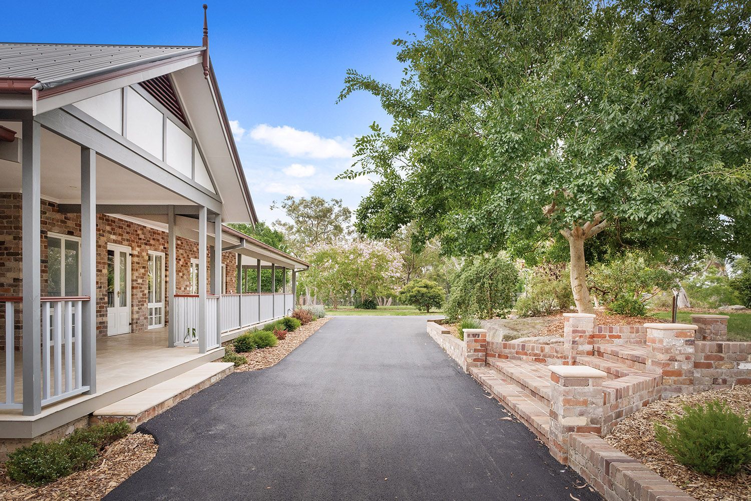 A driveway leading to a large house with a porch.