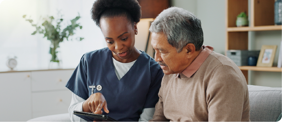 A nurse is showing an elderly man how to use a tablet.