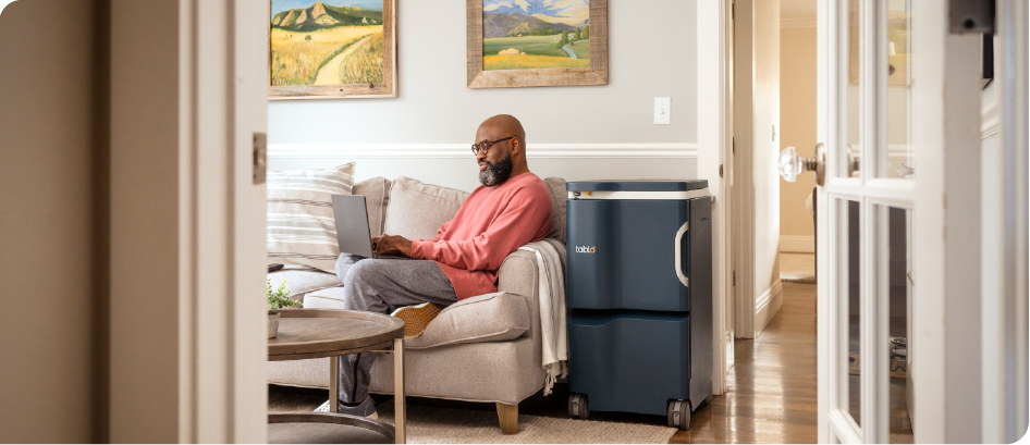 A man is sitting on a couch using a laptop computer.