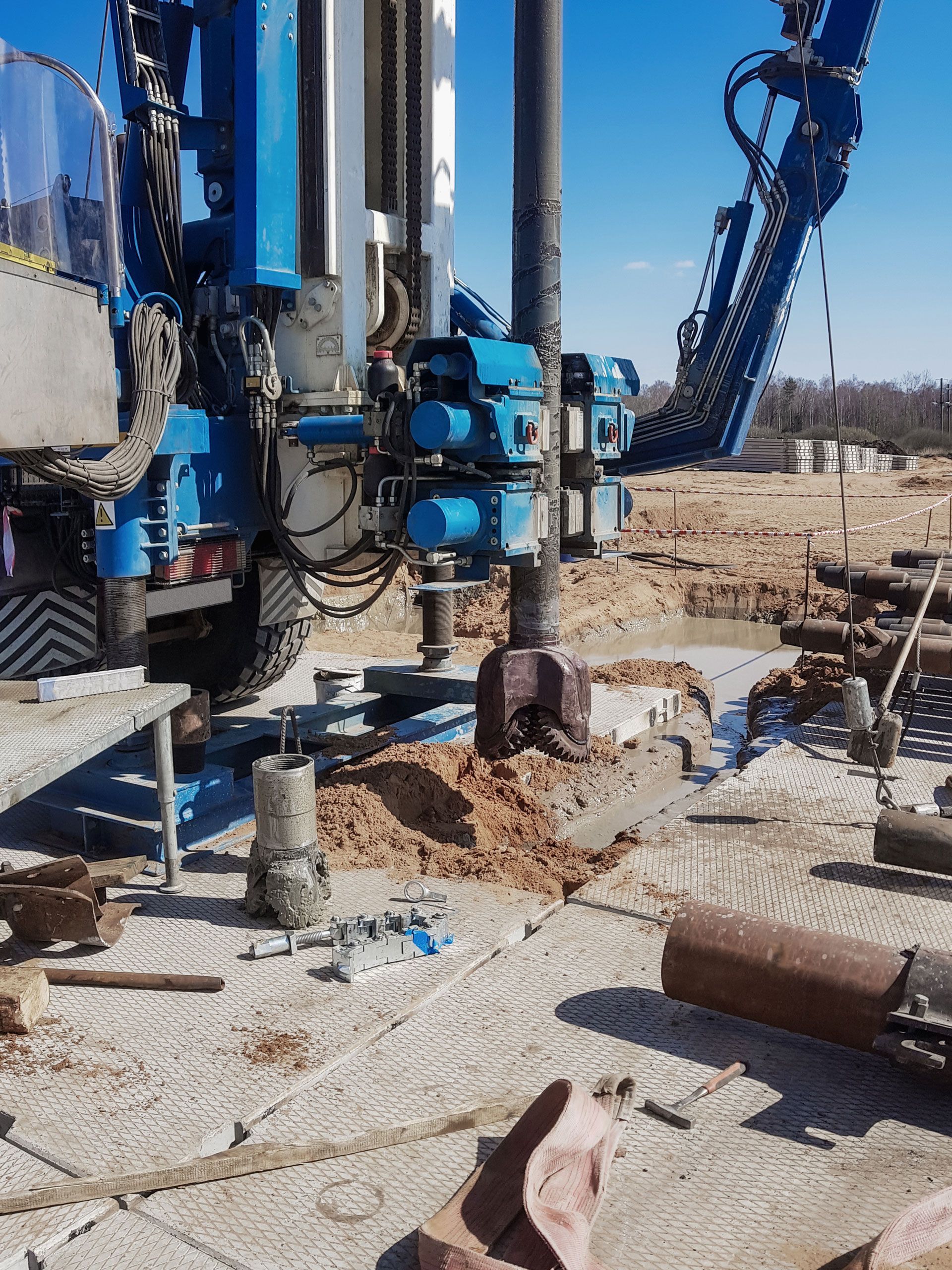 Blue drilling machine boring into the ground on a construction site.