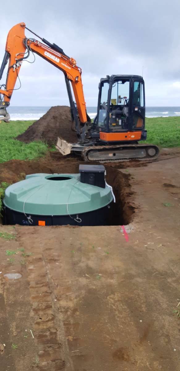 An excavator is digging a hole in the dirt in a field.