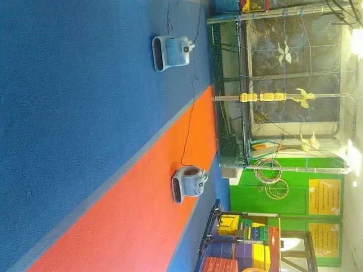 Two industrial air movers on a blue and orange floor inside a room with a trampoline and green wall panels.