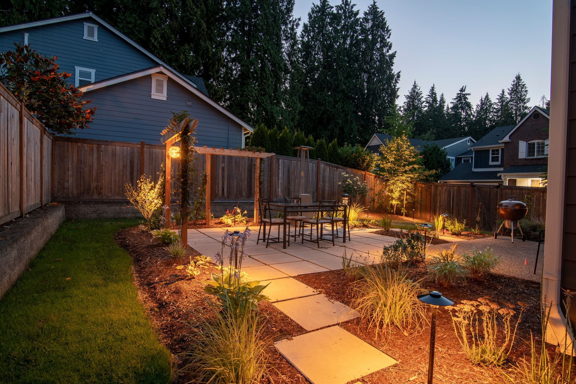 A backyard with a table and chairs and a fence at night.