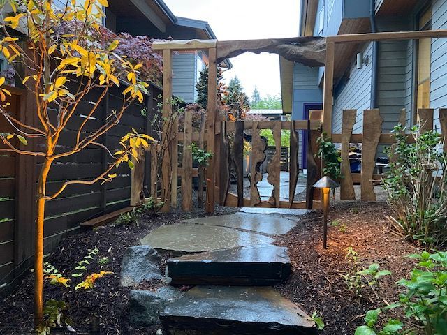 A lush green lawn is surrounded by trees and bushes in front of a house.