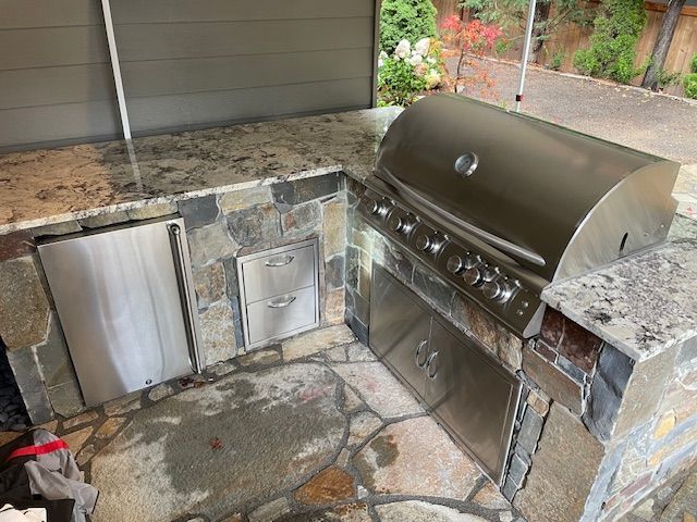 A stainless steel grill is sitting on top of a stone counter.