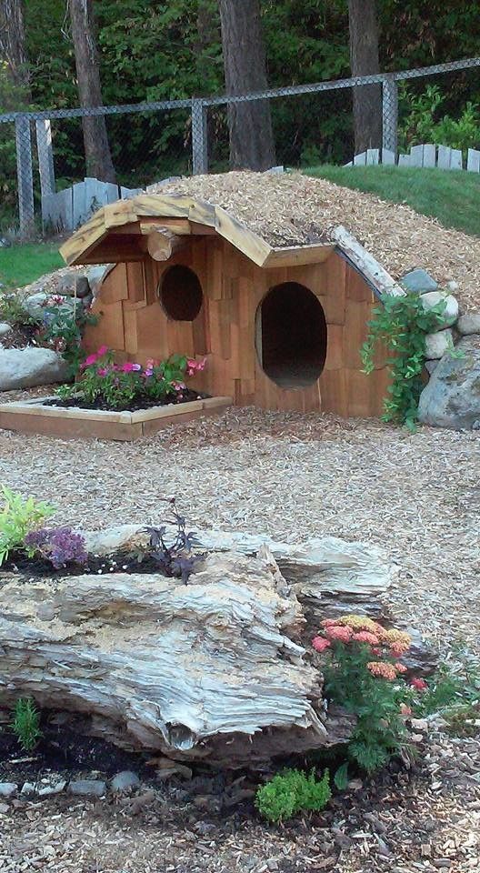 A wooden dog house is sitting in the middle of a rock garden.