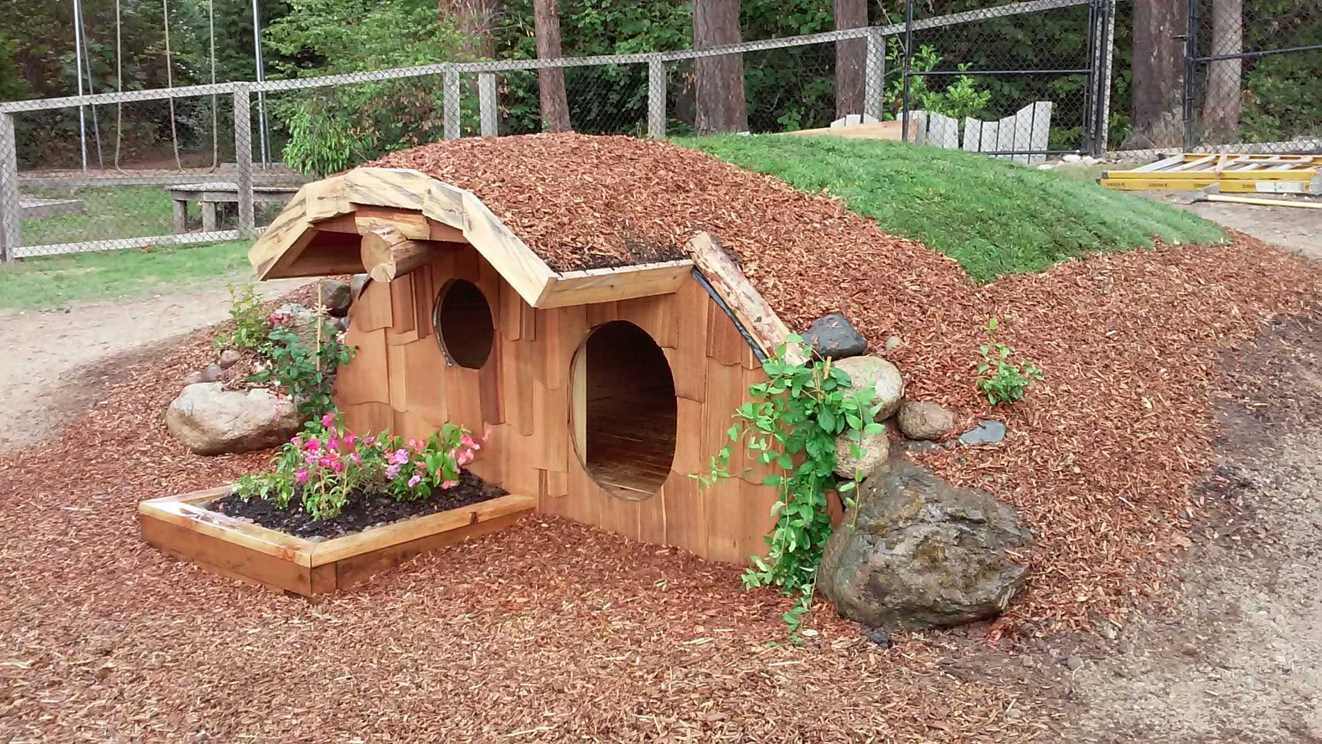 A wooden dog house is sitting on top of a pile of mulch.