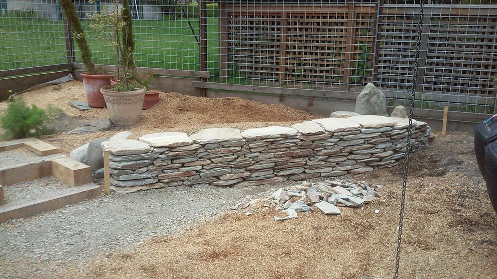 A stone wall is being built in a backyard.