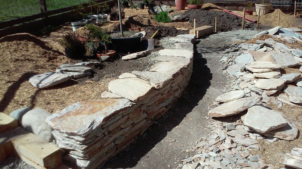 A stone wall is being built in a garden.