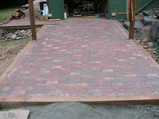 A brick walkway leading to a green building