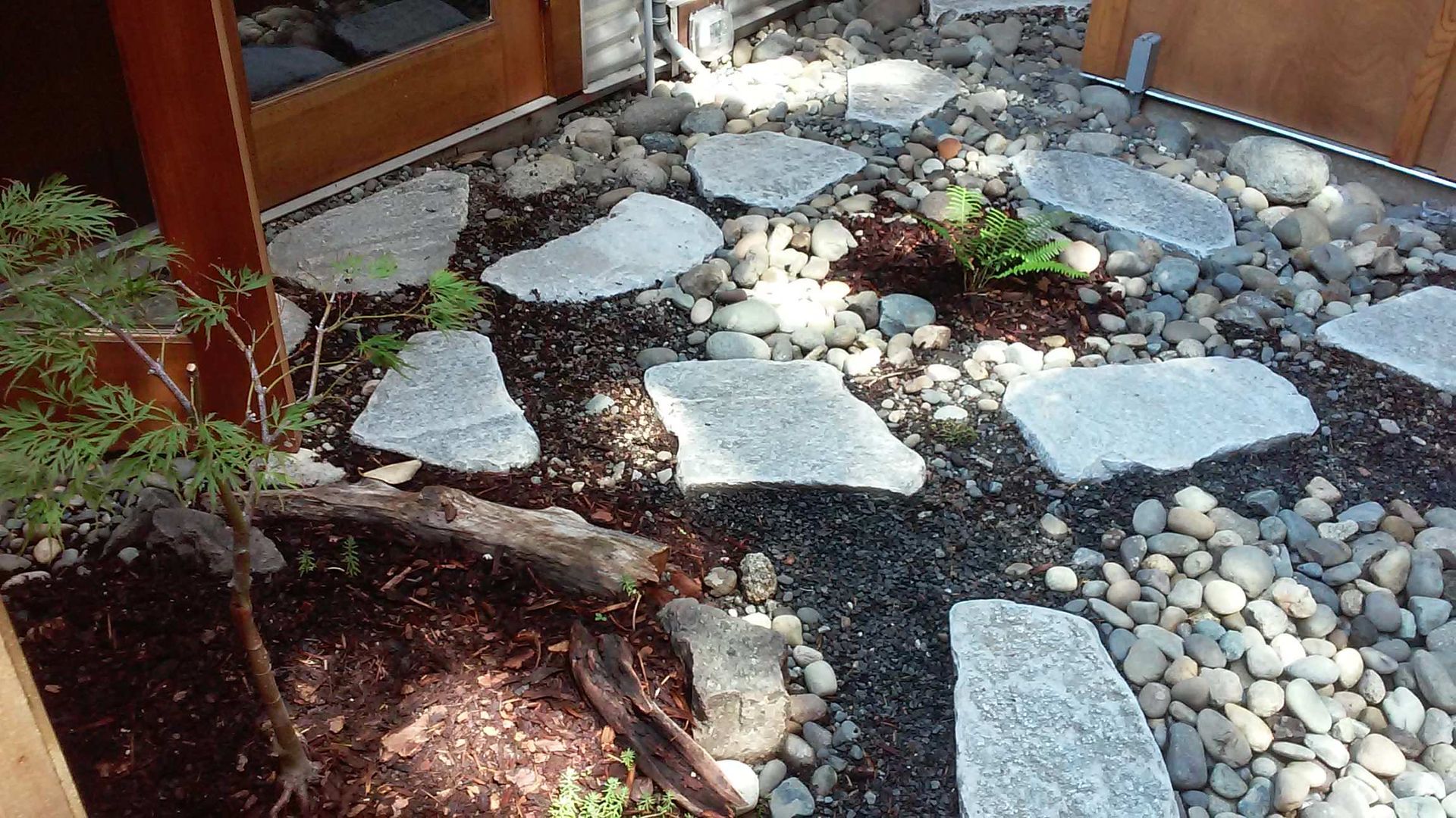 A stone walkway surrounded by rocks and mulch in a garden.